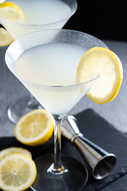 Lemon drop martini cocktail on gray stone and black background