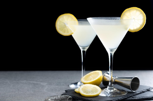 Cocktail martini goccia di limone su pietra grigia e sfondo nero