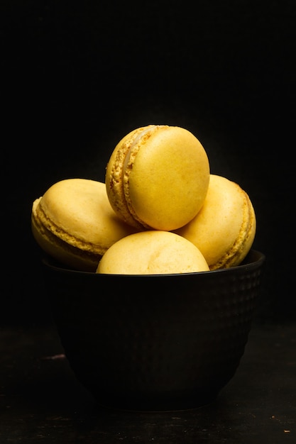 Lemon flavored macarons in a black bowl