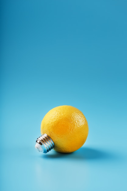 Lemon fruit as a light bulb on blue. The conceptual idea.