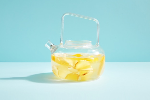 Lemon-ginger anti-virus drink in a stylish transparent brewing kettle