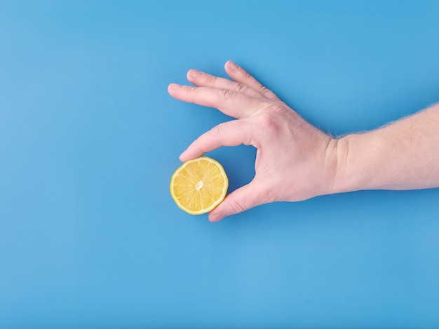 Lemon in hand on blue surface