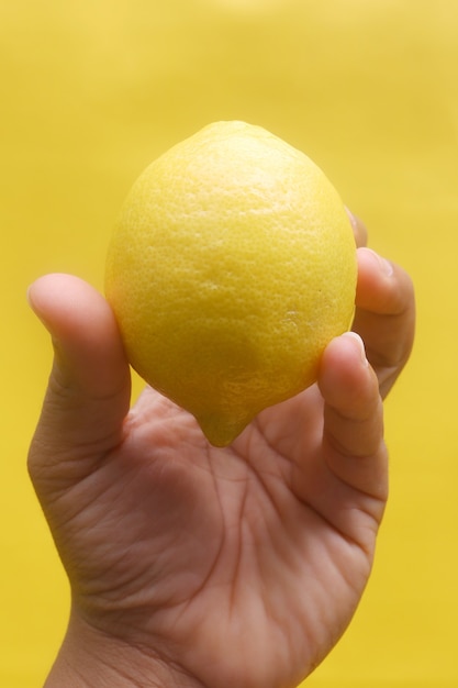 lemon in hand on with yellow background