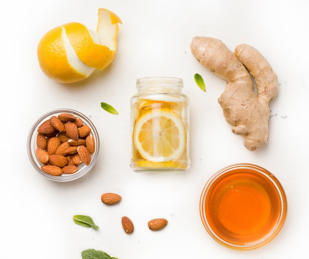 Lemon in honey-sugar syrup with ginger and mint in a jar on white