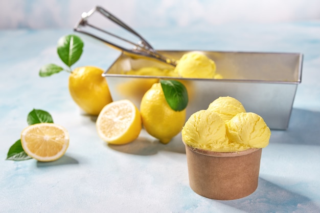 Lemon ice cream and fresh lemon  in paper cup on mint colors background