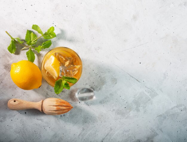 Lemon ice tea on concrete gray background with mint and ice