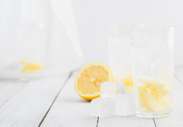 Lemon juice detox water. Mineral water infused with lemons. Wooden white table.