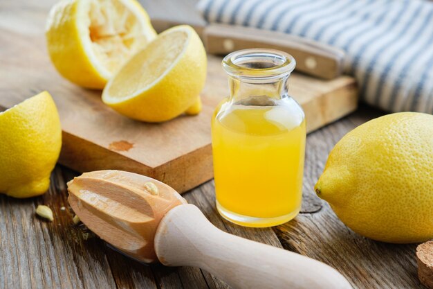 Lemon juice or oil bottle wooden juicer and lemon citrus fruits