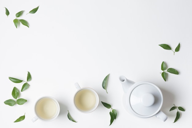 Lemon leaves with cup and teapot isolated on white background