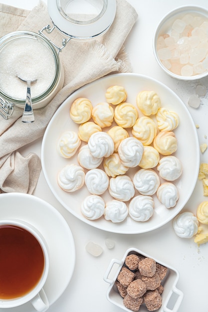 Lemon meringues and white on the background of tea, sugar on a white background. Top view, vertical.