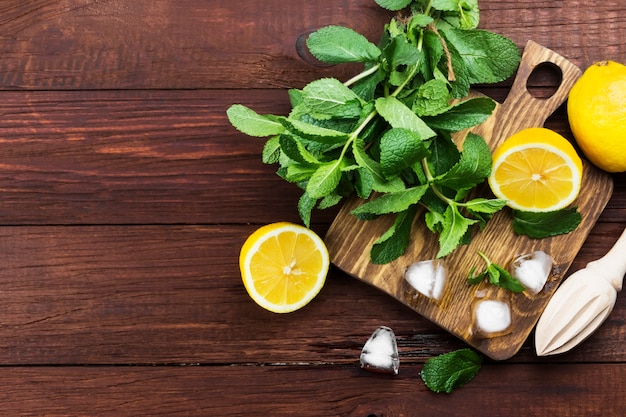 lemon, mint, ice on a wooden cutting board on a wooden background