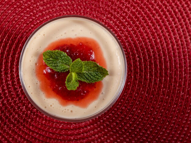 Lemon mousse in crystal bowl with strawberry jelly topping and mint.