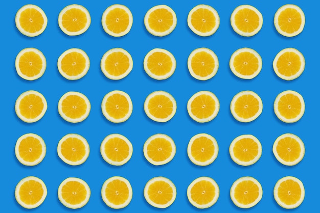 Lemon pattern yellow lemons slices on blue paper background trendy flat lay summer concept