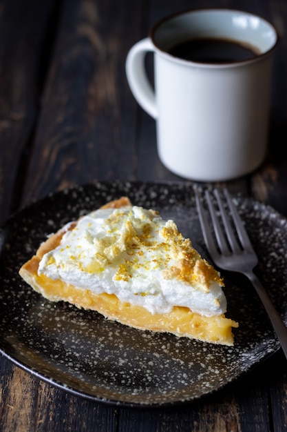 Lemon pie with meringue on a wooden background.