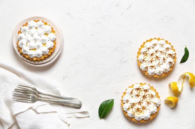 Lemon pies with meringue on a white background with copy space