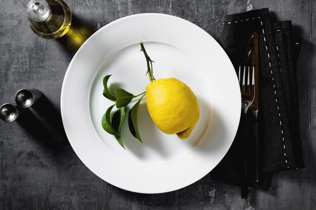 Lemon on a plate table setting tableware cutlery on a dark background