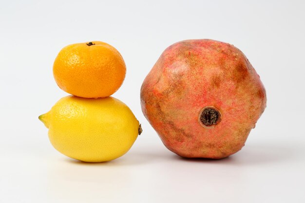 Lemon, pomegranate and mandarin on white background