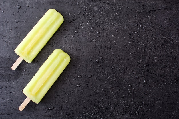 Lemon popsicles on black stone copy space