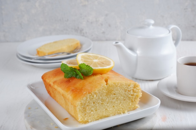 lemon pound cake met witte theepot en een kopje koffie met wazige achtergrond witte achtergrond