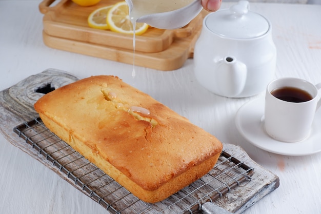 白いティーポットとぼやけた背景と白い背景のコーヒーのカップとレモンパウンドケーキ