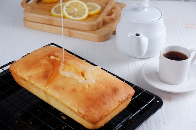 lemon pound cake with white teapot and a cup of coffee with blury backgroundwhite background