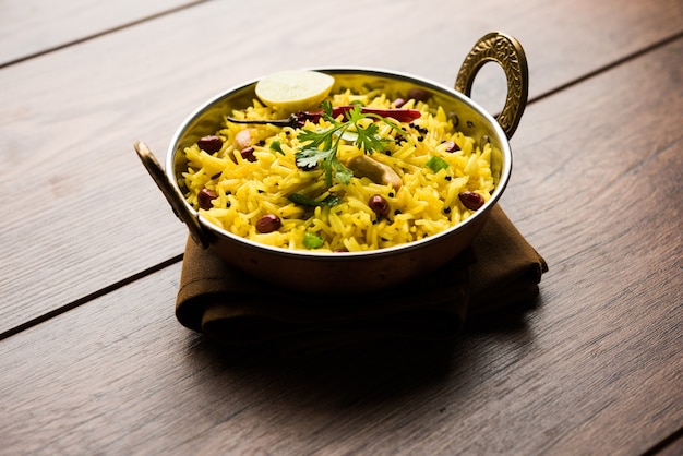 Lemon Rice or fodnicha bhat is South Indian turmeric rice or maharashtrian recipe using leftover rice garnished with nuts curry leaves and lemon juice, selective focus