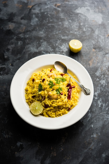 Lemon Rice or fodnicha bhat is South Indian turmeric rice or maharashtrian recipe using leftover rice garnished with nuts curry leaves and lemon juice, selective focus