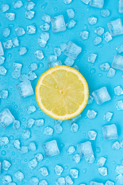 Lemon round slice above ice cubes on blue.