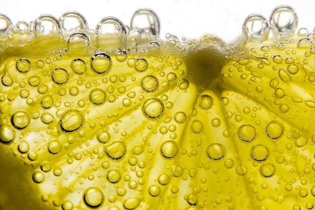 Lemon sliced in water with air spherical bubbles in background light closeup selective focus