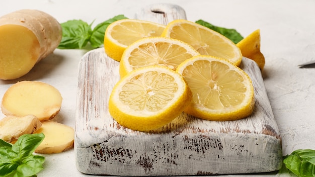 Lemon slices on a board with basil and ginger on the table