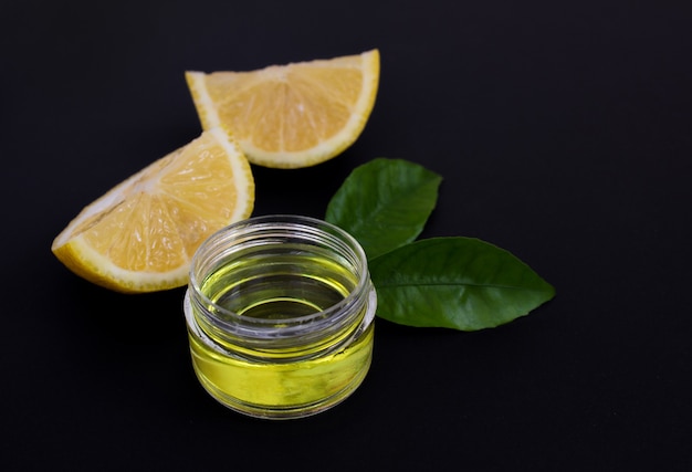 Lemon slices and cosmetic lemon oil on a black background close up