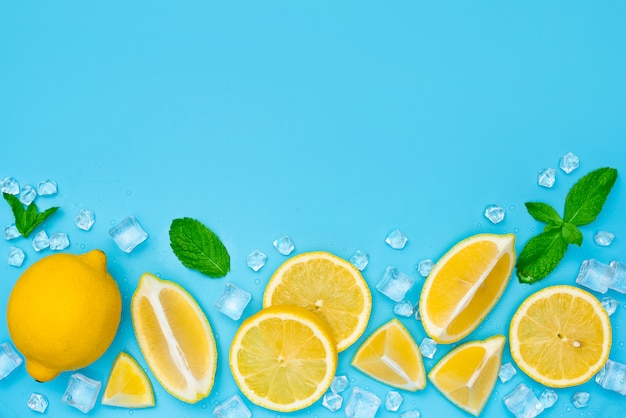 Lemon slices with ice and mint on blue