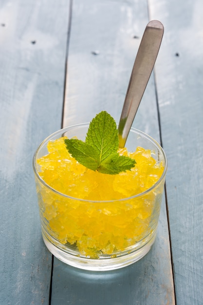 Lemon slushie in glass on blue wooden table