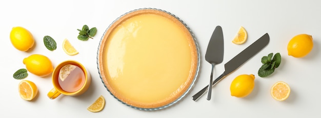 Lemon tart, mint and lemons on white background, top view