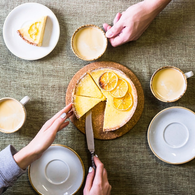 Lemon tart on the table among saucers and cups of coffee.
