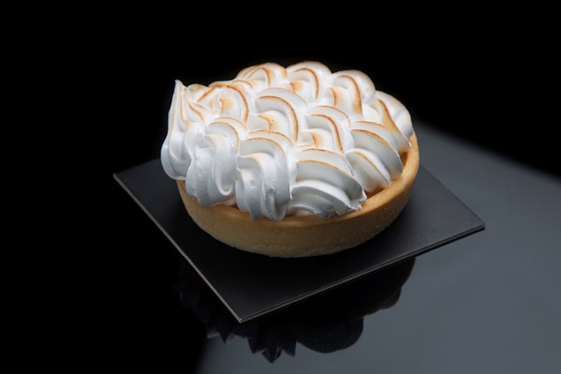 Lemon tart with meringue on black.