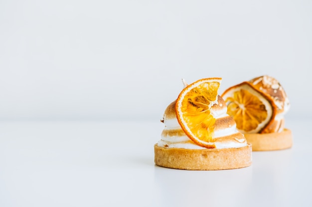 Лимонный десерт тарталетки с безе на белом фоне с копией пространства.