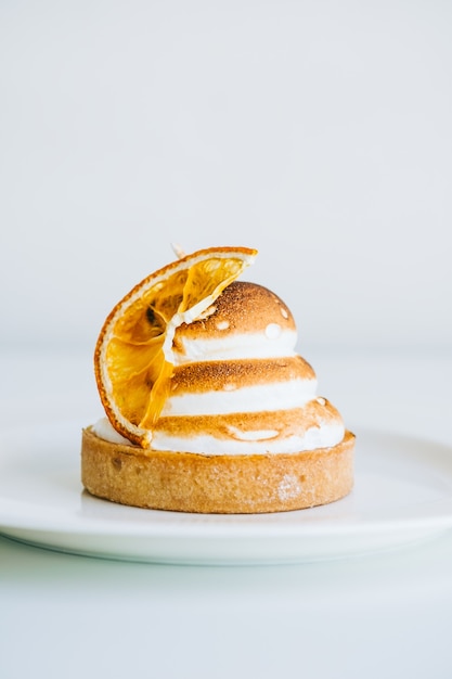 Lemon tartlet dessert with meringue on white background.