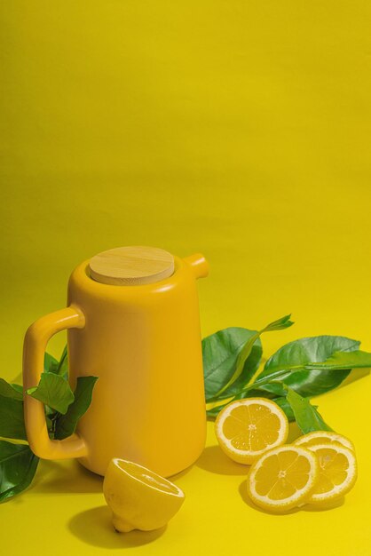 Foto tè al limone in teiera in ceramica con frutti maturi rinfresco bevanda stagionale sfondo concettuale con foglie verdi di agrumi spazio di copia con messa a fuoco selettiva in stile moderno