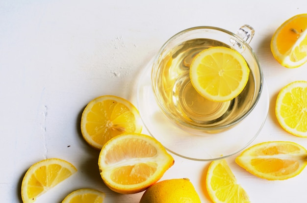 Lemon tea in a transparent cup on white background with slices of lemon