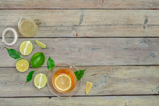 Tè al limone con limone e lime sul tavolo di legno dello sfondo