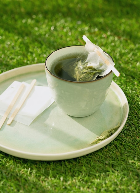 Lemon Verbena tea in a mug  with hand made teabag over a grass desk on the balcony. Coziness concept. Selective Focus. Close up. Natural light.