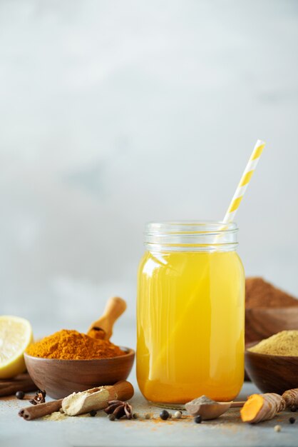 Lemon water with ginger, curcuma, black pepper. Vegan hot drink concept. Ingredients for orange turmeric drink on grey concrete background