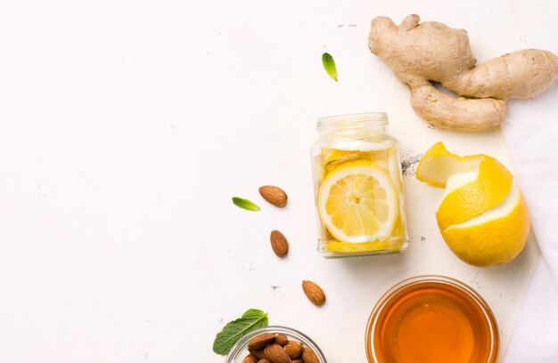 Lemon with honey, ginger, mint and almonds in a jar on white