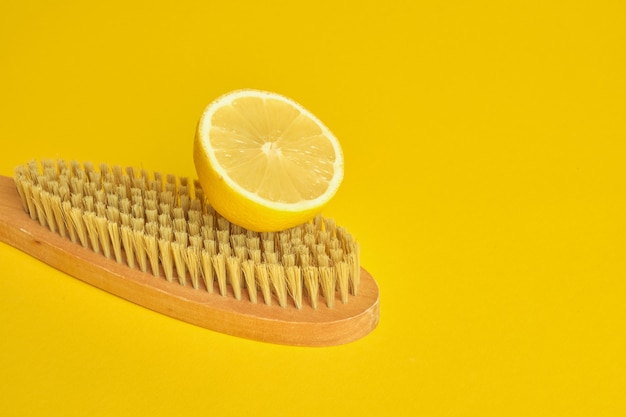 lemon and wooden brush on yellow background