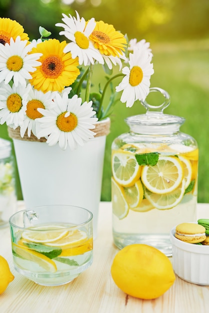 Lemonade and daisy flowers on table. Mason jar glass of lemonade with lemons. Outdoor picnic.