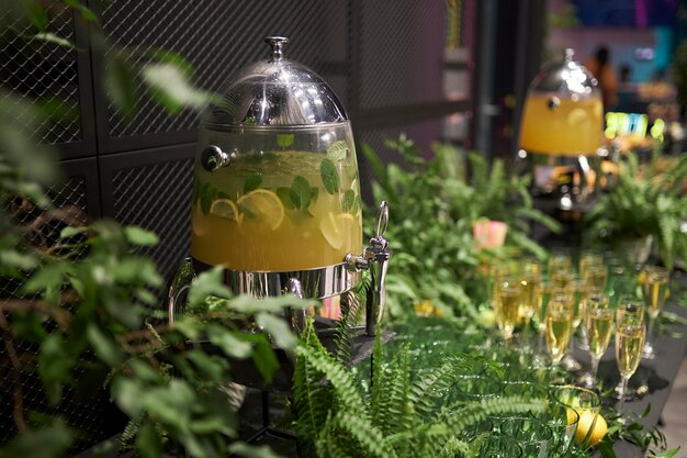 Lemonade in a dispenser on a table decorated with fresh herbs and flowers