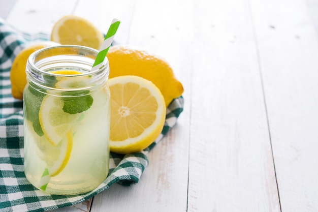 Foto bevanda della limonata in un vetro del barattolo sulla tavola di legno bianca