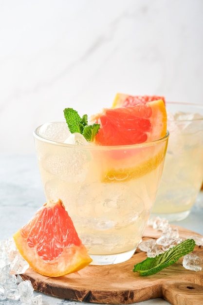 Lemonade drink made from grapefruit, soda water and mint leaves with ice on light blue concrete surface. Top view.