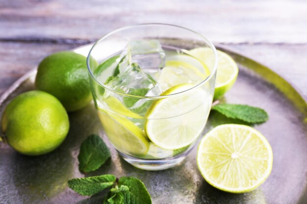 Lemonade in glass on tray on wooden background